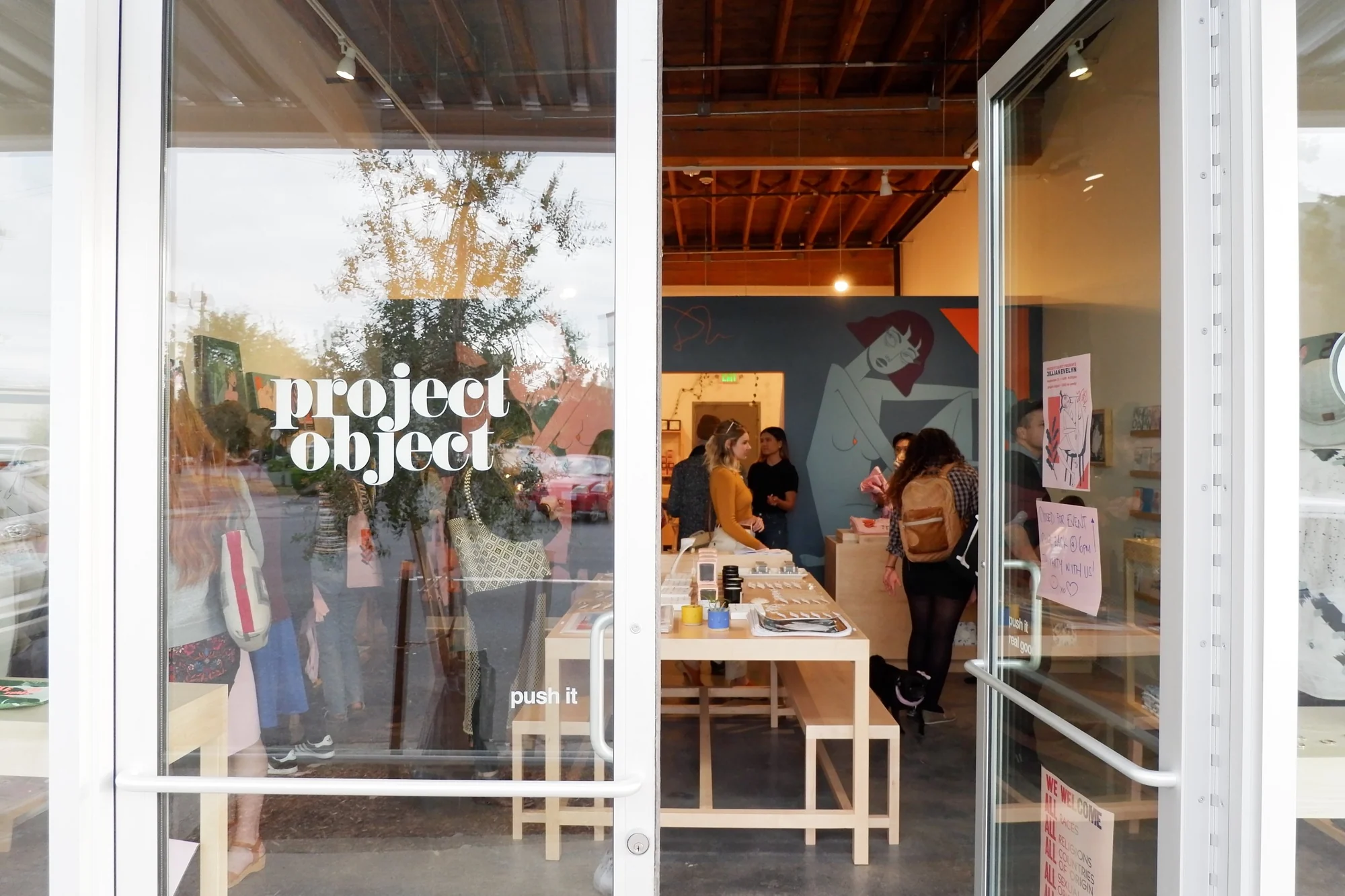 The glass shop door with the project object logo, opened onto a busy interior of visitors.