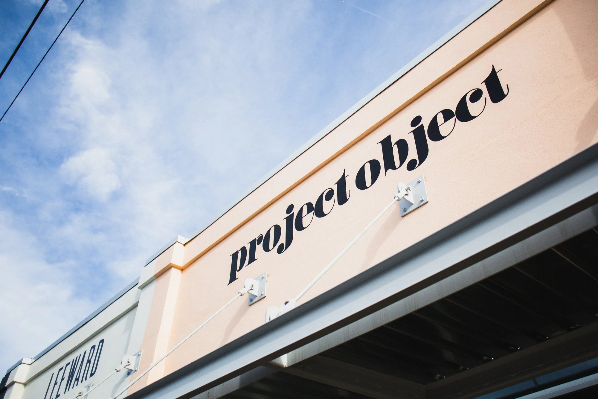 The project object wordmark painted in black on a peach wall above the shop entrance, against a blue sky.